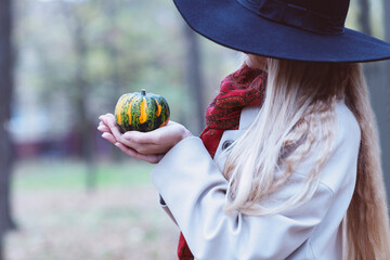 Portrait of the beautiful woman wearing black hat holding little pumpkin