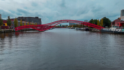 Aerial drone view of modern footbridge Python Bridge at Eastern Docklands neighborhood of Amsterdam...