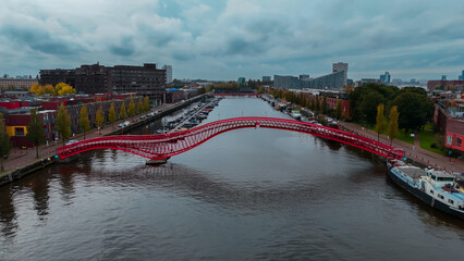 Aerial drone view of modern footbridge Python Bridge at Eastern Docklands neighborhood of Amsterdam...