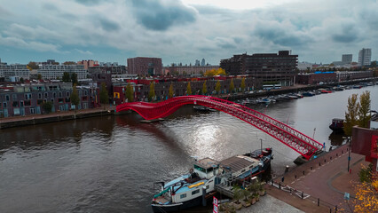 Aerial drone view of modern footbridge Python Bridge at Eastern Docklands neighborhood of Amsterdam...