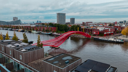 Aerial drone view of modern footbridge Python Bridge at Eastern Docklands neighborhood of Amsterdam...