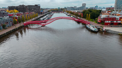 Aerial drone view of modern footbridge Python Bridge at Eastern Docklands neighborhood of Amsterdam...