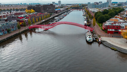 Aerial drone view of modern footbridge Python Bridge at Eastern Docklands neighborhood of Amsterdam...