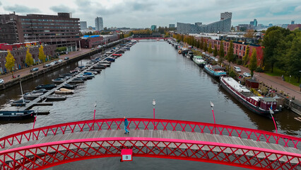 Aerial drone view of modern footbridge Python Bridge at Eastern Docklands neighborhood of Amsterdam...