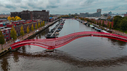 Aerial drone view of modern footbridge Python Bridge at Eastern Docklands neighborhood of Amsterdam...