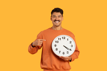 Happy guy with clock showing punctuality on yellow