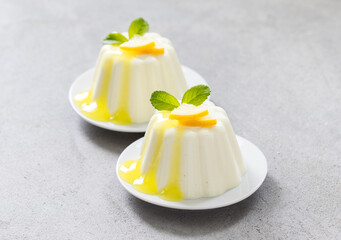 Lemon cream pudding, Panna Cotta with lemon sauce, on a plate. Light grey background. Close-up