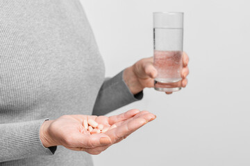 Senior holding pills and a glass of water