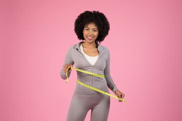 Happy lady with measuring tape on pink background