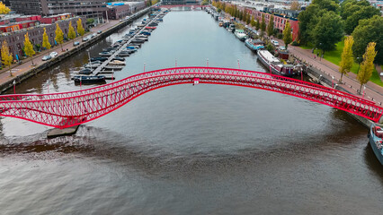 Aerial drone view of modern footbridge Python Bridge at Eastern Docklands neighborhood of Amsterdam Netherlands - obrazy, fototapety, plakaty