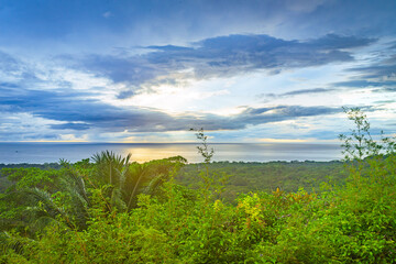Sunset over a lush tropical landscape with ocean views, where rays break through the cloud cover. High quality photo. Uvita Puntarenas Province Costa Rica