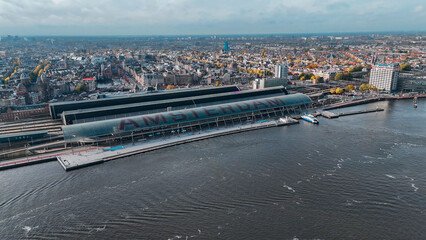 Obraz premium Aerial drone view Amsterdam Central Train Station with Amsterdam sign on roof. Bird's eye view autumn cityscape