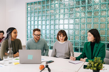 Modern corporate office open space with busy male and female staff employees using laptop computers sitting at work in big modern corporate office. Startup team working together at creative open space