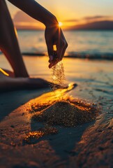Close up of a woman's hand in the sand, pouring golden sand on a beach at sunset. 