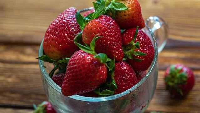 Red ripe strawberries in a cup rotating on a wooden table. Juicy Fresh Ripe Scarlet Red Strawberries, Summer Useful Berries. The Concept Of The Right To Natural Healthy Food.