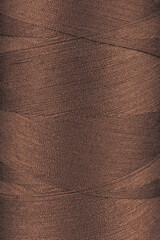 Texture of brown color threads in spool close up, macro. Sewing threads bobbin abstract background,...