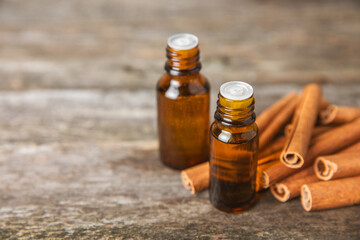 Cinnamon aromatic essential oil and cinnamon sticks on a wooden background. Aromatherapy. Organic cosmetic oil. Spa concept. Place for text. Copy space.