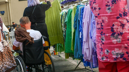 Disabled person in a wheelchair buying things choosing clothes at the market in a store at a fair...