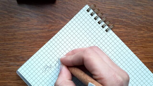 Be yourself Writing motivational phrase on notepad page placed on wooden surface. Writing down text with a pen on a blank sheet.