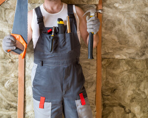 a builder in uniform with tools in his hands and in pockets on the chest of the uniform against the...