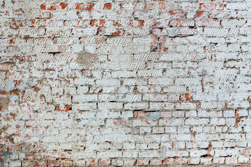 Old red brick wall with peeling plaster..
