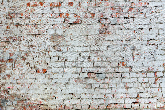 Old red brick wall with peeling plaster..
