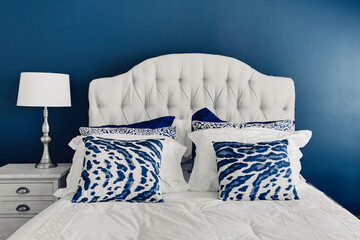 Comfortable and Stylish Bedroom with A Tufted White Headboard and Blue and White Patterned Pillows...