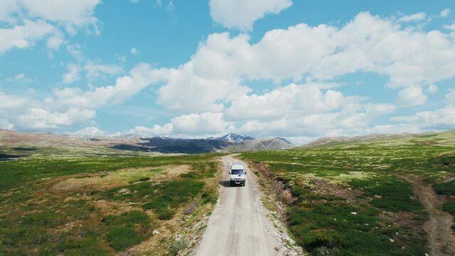 Aerial shot of epic mountain gravel road in national park. Overland travel adventure, road trip with camper van. Off grid van with solar panel setup on roof. Explore off road destination