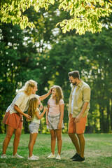 Fototapeta premium A happy family of four standing on meadow in nature and having fun.