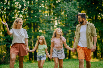 Fototapeta premium Portrait a happy family taking a walk on meadow near forest in nature.