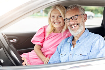 Happy elderly couple, man driving and woman smiling