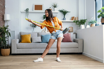 Funny motivated woman dancing and listening to music while sweeping the house