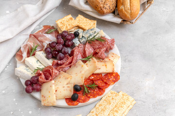 Food antipasto prosciutto ham, salami, olives and grissini bread sticks. cheese on a board parmesan, pecorino, gorgonzola. Charcuterie board. Two glasses of red wine 