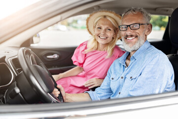 Happy elderly couple in car with window down - obrazy, fototapety, plakaty
