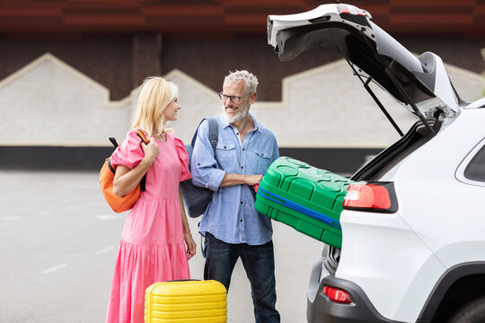 Retired couple standing by open car trunk