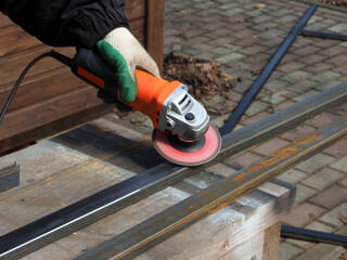 A worker processes metal with an angle grinder on a construction site.
The concept of locksmith work, processing of metal products.
