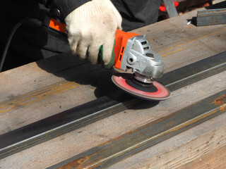 A worker processes metal with an angle grinder on a construction site.
The concept of locksmith work, processing of metal products.
