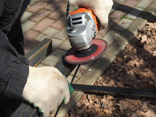 A worker processes metal with an angle grinder on a construction site.
The concept of locksmith work, processing of metal products.
