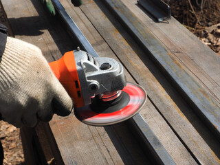 A worker processes metal with an angle grinder on a construction site.
The concept of locksmith work, processing of metal products.
