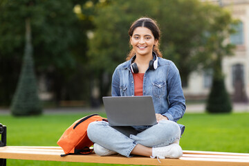 Relaxed woman student studying outdoors with laptop