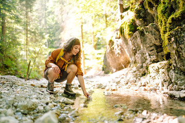 Woman draws clean spring water from the mountain creek. Travel, adventure. Concept of an active...