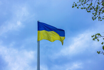 Ukrainian flag on a pole over dramatic blue sky with copy space. Flag of Ukraine on flag stock over blue sky.