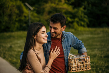 Couple walks together in the park with a picnic baske