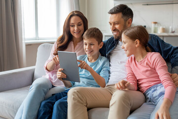Family gathered around a digital tablet, home interior