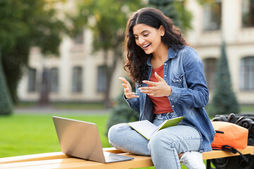 Indian woman student laughing and using laptop