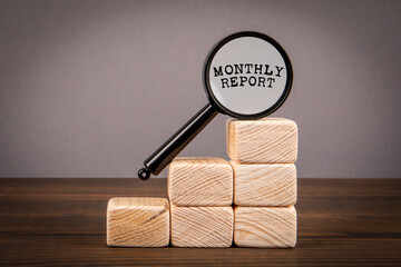 Monthly Report Concept. Magnifying glass and wooden blocks - 784773739