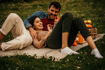 Young couple relaxing together with a picnic basket in a beautiful park