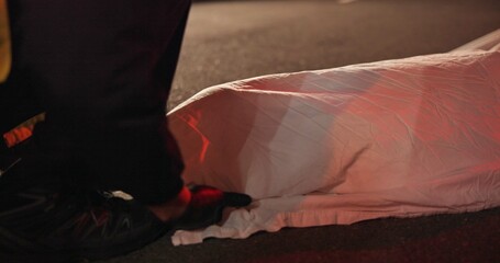 Crime scene, dead body and cover for accident at night in road, street or outdoor with paramedic or...