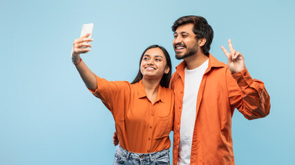 Happy couple taking a selfie together on blue background