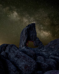 Galaxy milky way surrounded by stars with a hollowed rock on foreground	